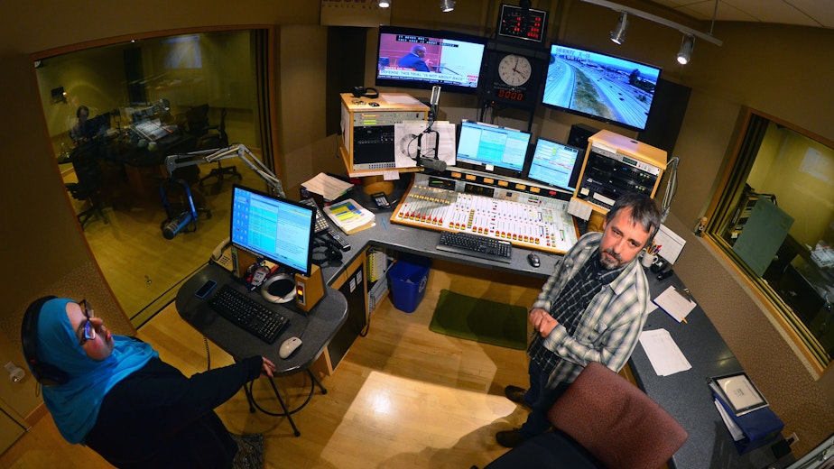 caption: 'The Record' producer Amina Al-Sadi and announcer Bernard Ouellette in the KUOW control room.