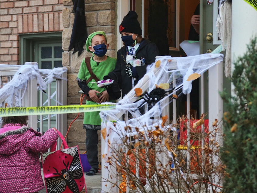 caption: Children wear face masks to protect them during the pandemic while trick-or-treating on Halloween night in Thornhill, Ontario, Canada, on Oct. 31, 2020.