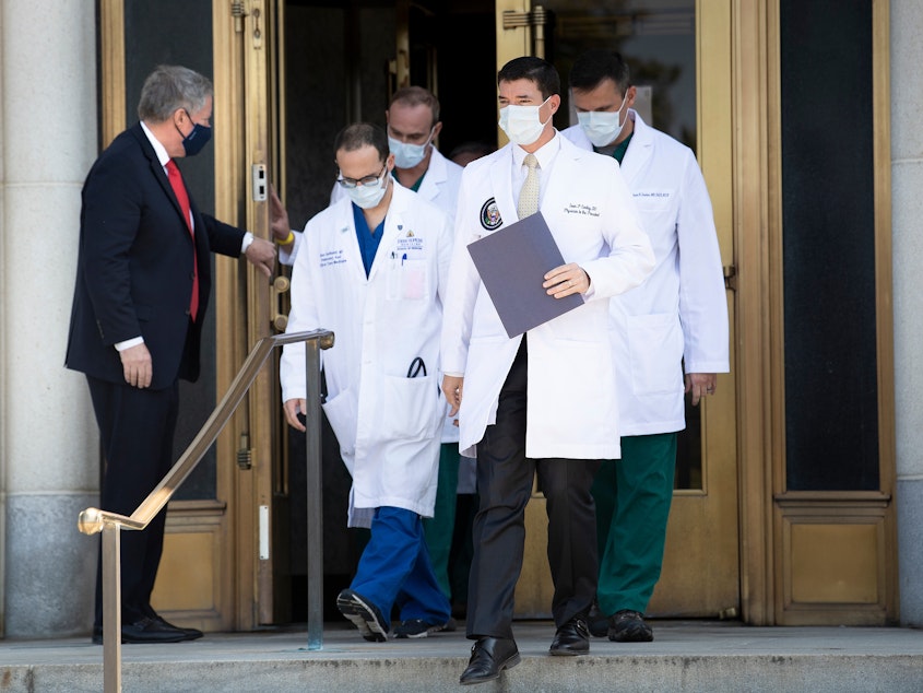 caption: White House chief of staff Mark Meadows holds the door for Dr. Sean Conley and other members of the president's medical team on Sunday. Another update on Trump's condition is expected sometime on Monday.
