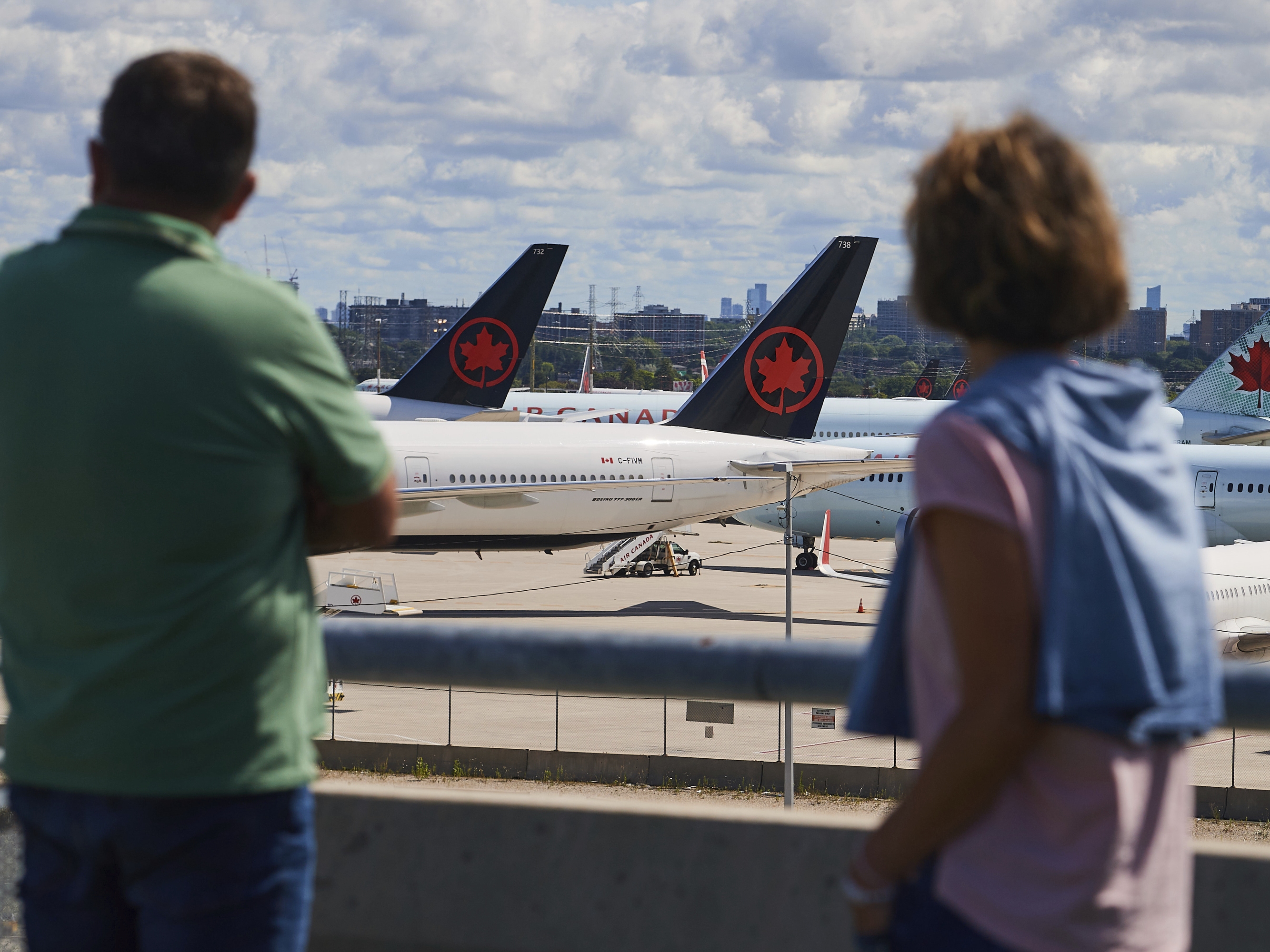 caption: Travelers look out over grounded Air Canada planes as flight attendants picket at Pearson International Airport in Toronto, Monday.