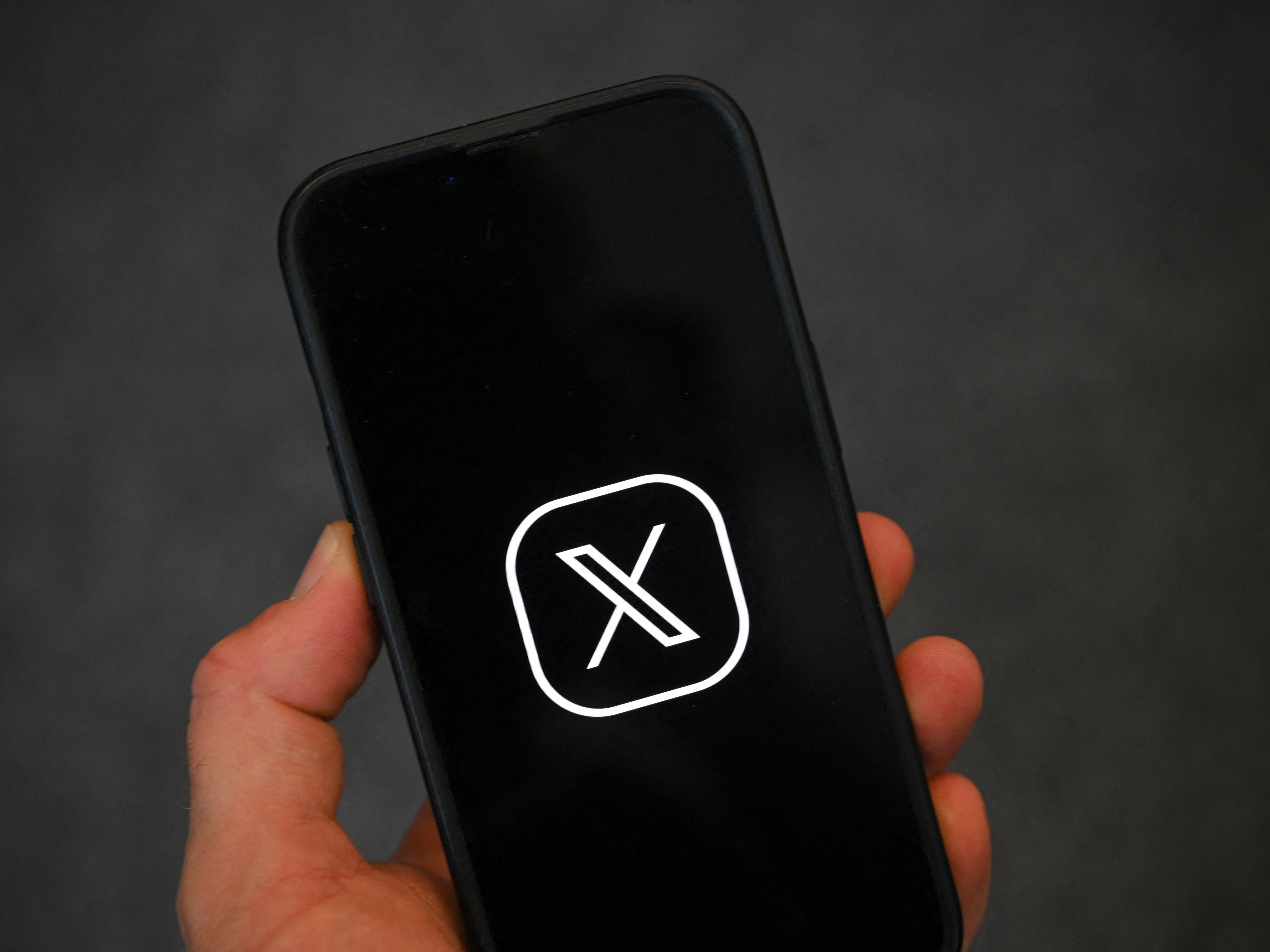 caption: The logo of social network X, formerly Twitter, on a smartphone. A new feature of the site gives more information about where accounts are primarily based from.
