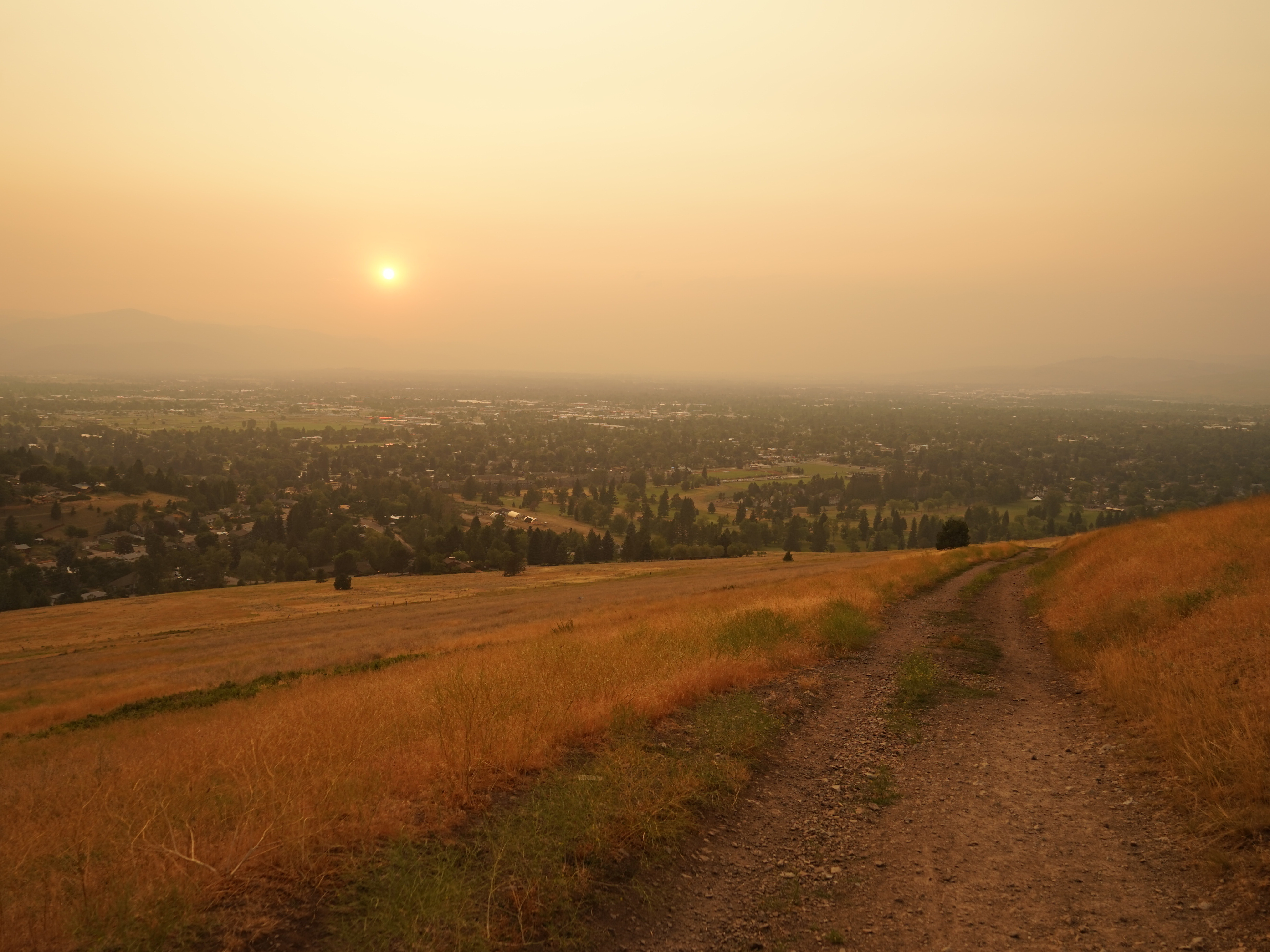 caption: Wildfire smoke blankets Missoula, Mont., at the end of a hot summer day. The mountain town has been inundated with smoke for weeks this summer.