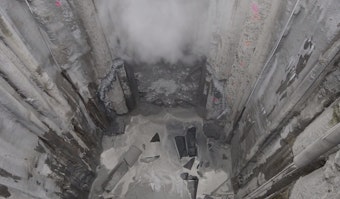 caption: Bertha, the tunnel boring machine, emerges from more than a year of captivity. The machine's turbines can be seen beneath the plume of dust.