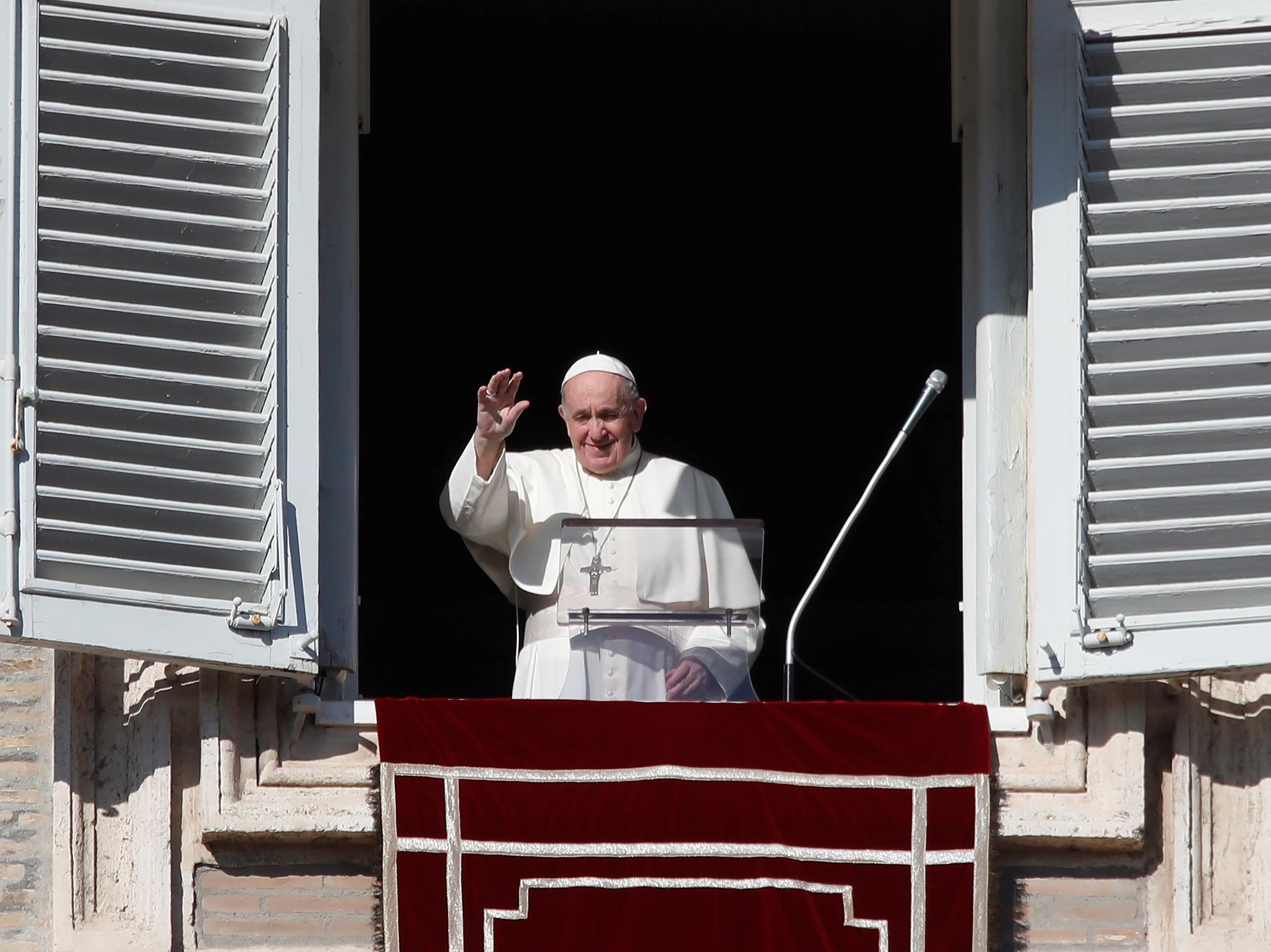 caption: Pope Francis waves as he arrives for the Angelus noon prayer from the window of his studio overlooking St. Peter's Square, at the Vatican, Sunday.
