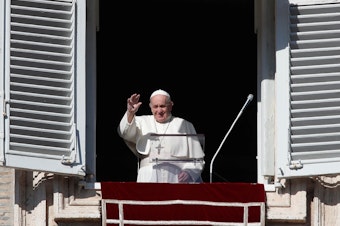 caption: Pope Francis waves as he arrives for the Angelus noon prayer from the window of his studio overlooking St. Peter's Square, at the Vatican, Sunday.