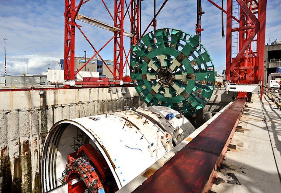 caption: A 120-foot-deep shaft being dug to gain access to the tunnel machine's cutter head (shown here being installed before tunneling began) may have led the Alaskan Way Viaduct to sink an inch last month.
