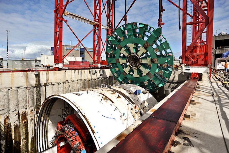 caption: A 120-foot-deep shaft being dug to gain access to the tunnel machine's cutter head (shown here being installed before tunneling began) may have led the Alaskan Way Viaduct to sink an inch last month.