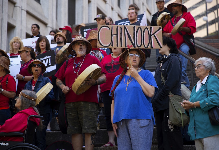 caption: Rachel Kidd, 57, in blue, gathers with other members of the Chinook Indian Nation and allies on the steps of the Henry M. Jackson Federal Building on Monday, August 29, 2022, during a rally for the restoration of federal recognition for the Chinook Indian Nation, in Seattle.