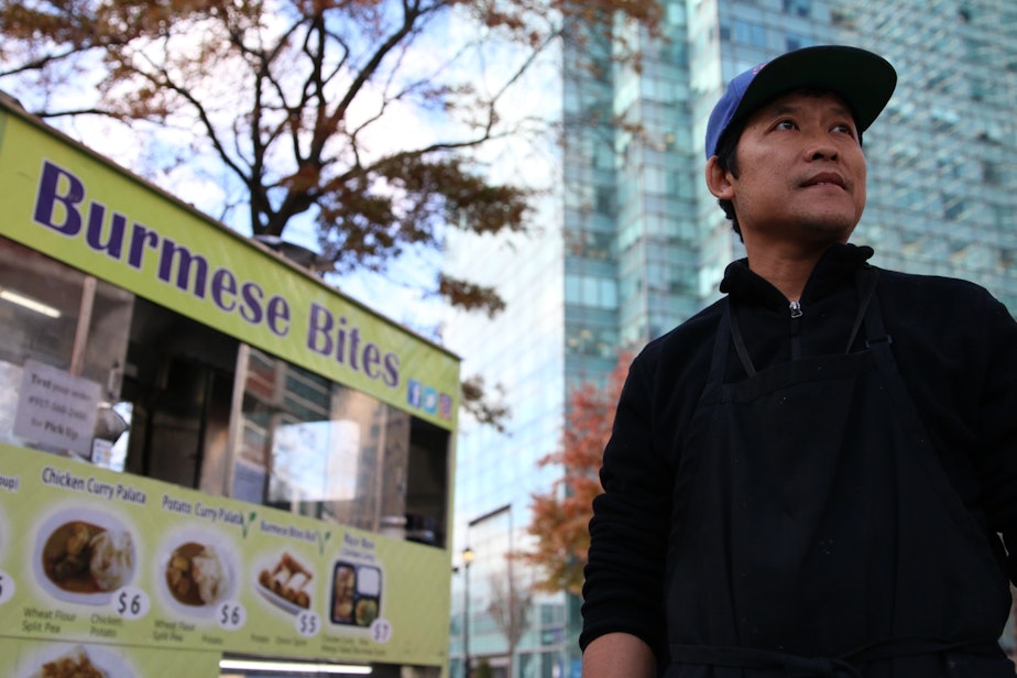 caption: Myo Lin Thwey hopes he can make a good living selling Burmese food to Amazon workers on the street. Behind him: the Citibank tower in Long Island City. Eventually it will be filled with Amazon workers.