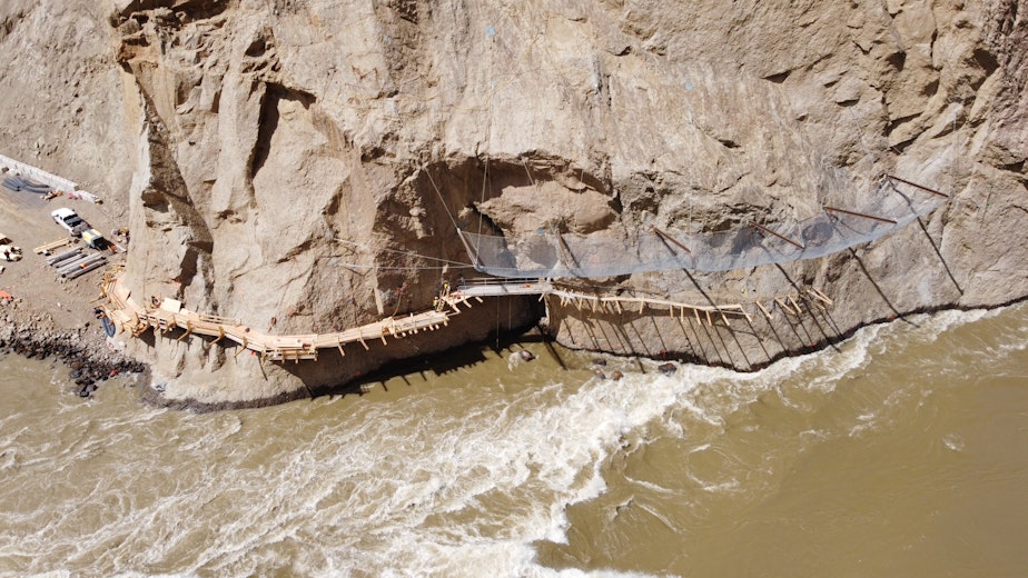 caption: Workers install supports for a pneumatic "salmon cannon," designed to suction fish past obstacles, at the Big Bar landslide on Canada's Fraser River.