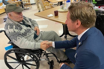 caption: Stanley Piper talks with Rep. Dean Phillips, D-Minn., at the New Hampshire Veterans Home in Tilton, N.H. on Dec. 8, 2023.