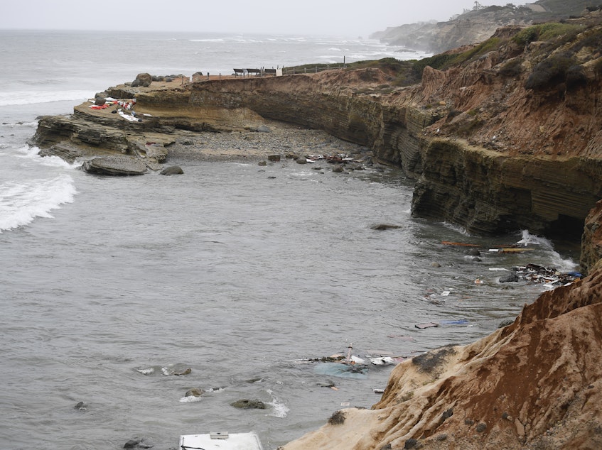 caption: Wreckage from a capsized boat washes ashore at Cabrillo National Monument near where a boat capsized off the San Diego coast Sunday. Authorities say four people were killed and two dozen others injured.