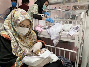 caption: An Afghan woman feeds a newborn rescued and brought to Ataturk National Children's Hospital in Kabul in May 2020 after gunmen attacked a maternity ward operated by Doctors Without Borders. The nonprofit runs clinics and hospitals in parts of the country — and is continuing its work following the Taliban takeover.