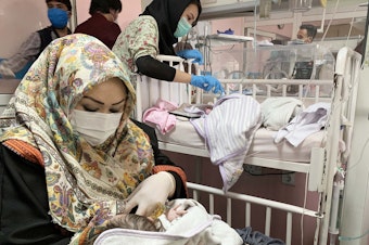 caption: An Afghan woman feeds a newborn rescued and brought to Ataturk National Children's Hospital in Kabul in May 2020 after gunmen attacked a maternity ward operated by Doctors Without Borders. The nonprofit runs clinics and hospitals in parts of the country — and is continuing its work following the Taliban takeover.