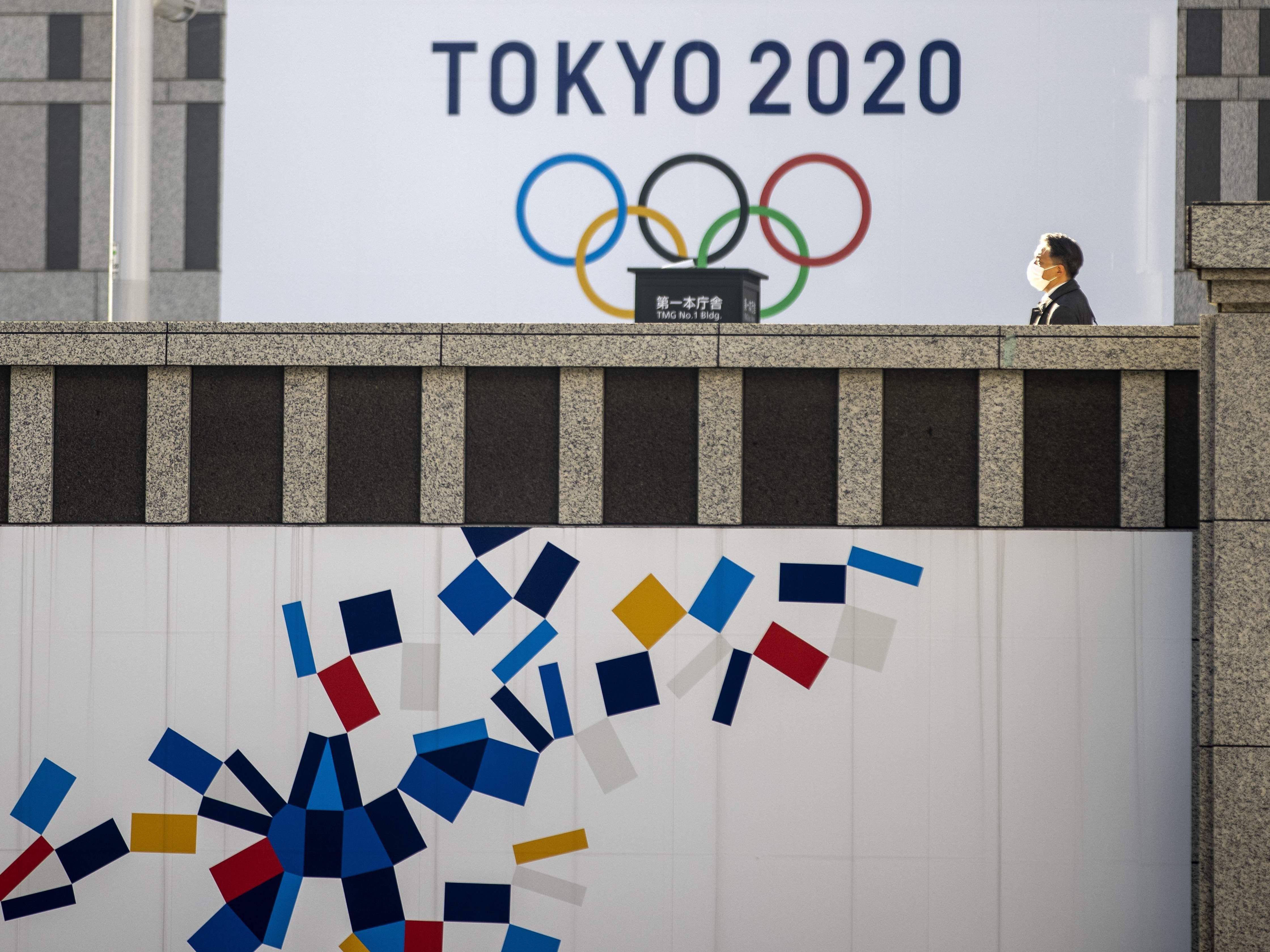 caption: A pedestrian walks past an official Tokyo 2020 Olympic Games banner hanging on the Tokyo Metropolitan Government Building on Friday.