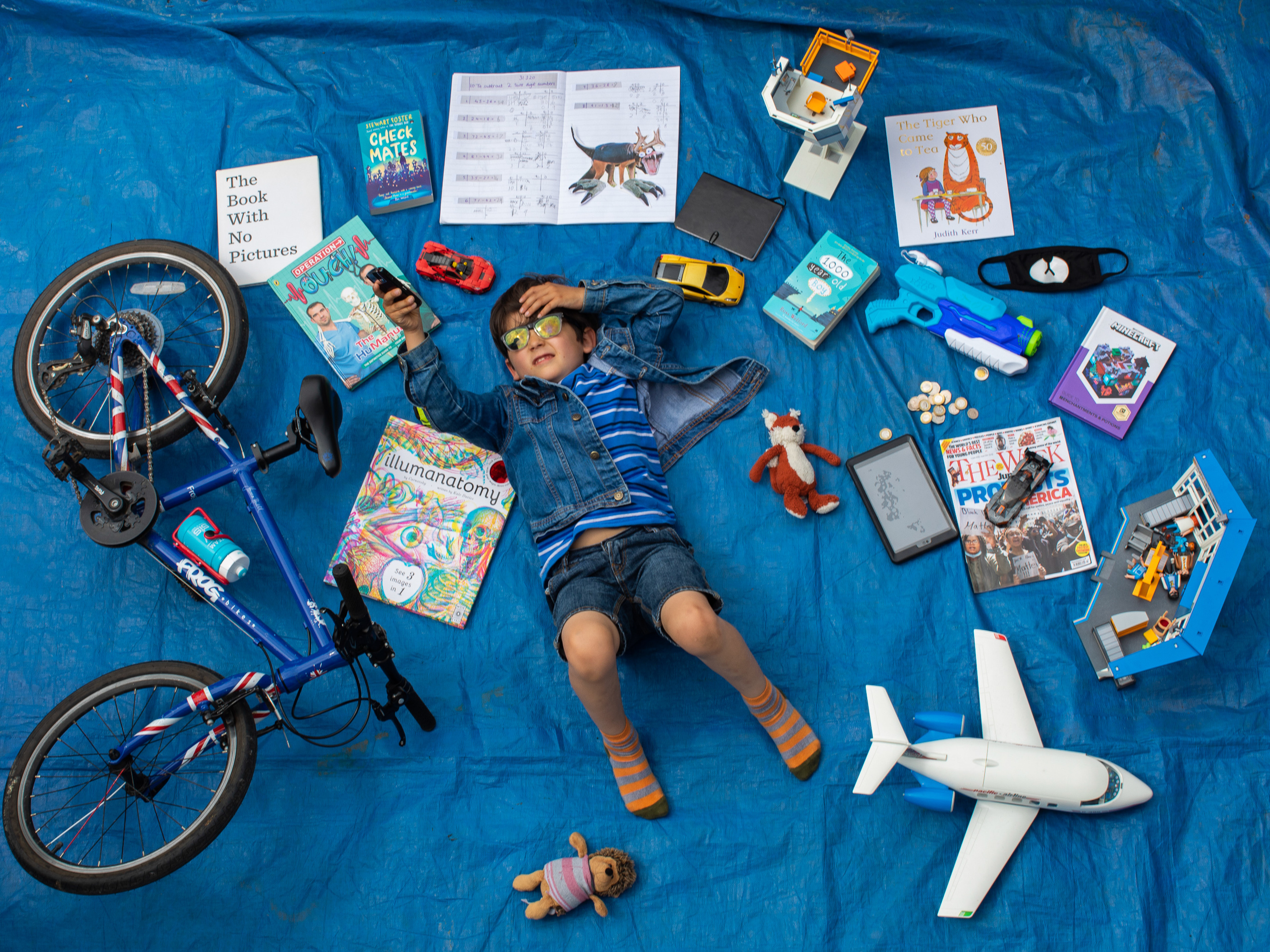 caption: Elizabeth Dalziel's son Joe, 7, lays next to his favorite objects, toys and books as part of a homeschooling assignment — to create a time capsule — from his school in Berkhamsted, England.