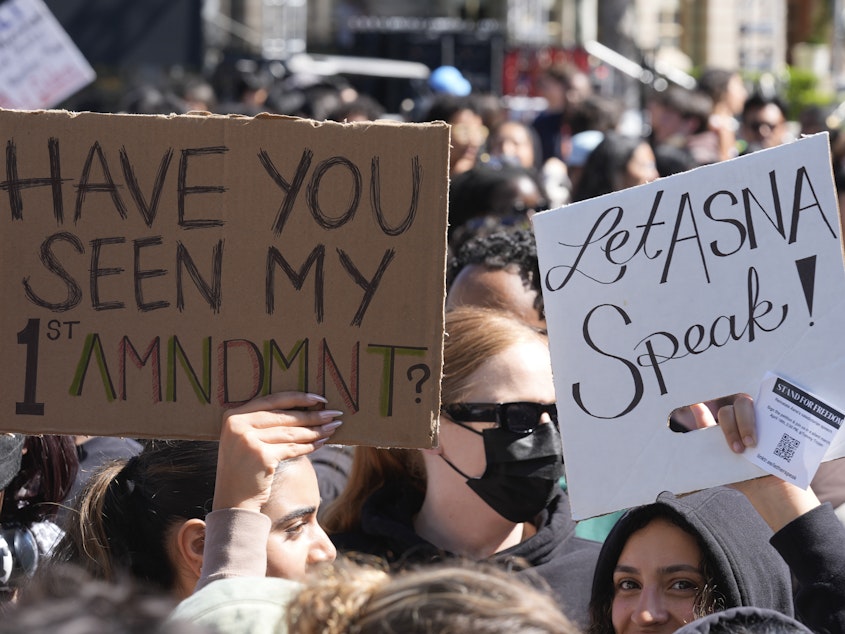 caption: Students carrying signs on April 18, 2024 on the campus of USC protest a canceled commencement speech by its 2024 valedictorian who has publicly supported Palestinians.