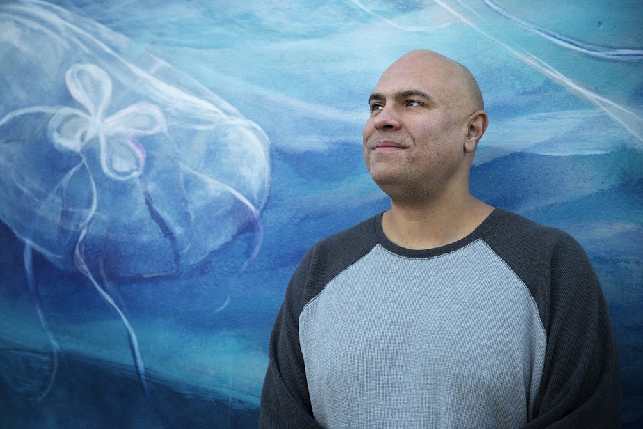 caption: Mark Mendez poses for a portrait in front of a mural painted by Esteban Camacho Steffensen on Thursday, December 6, 2018, on Northeast 127th Street in Seattle. 