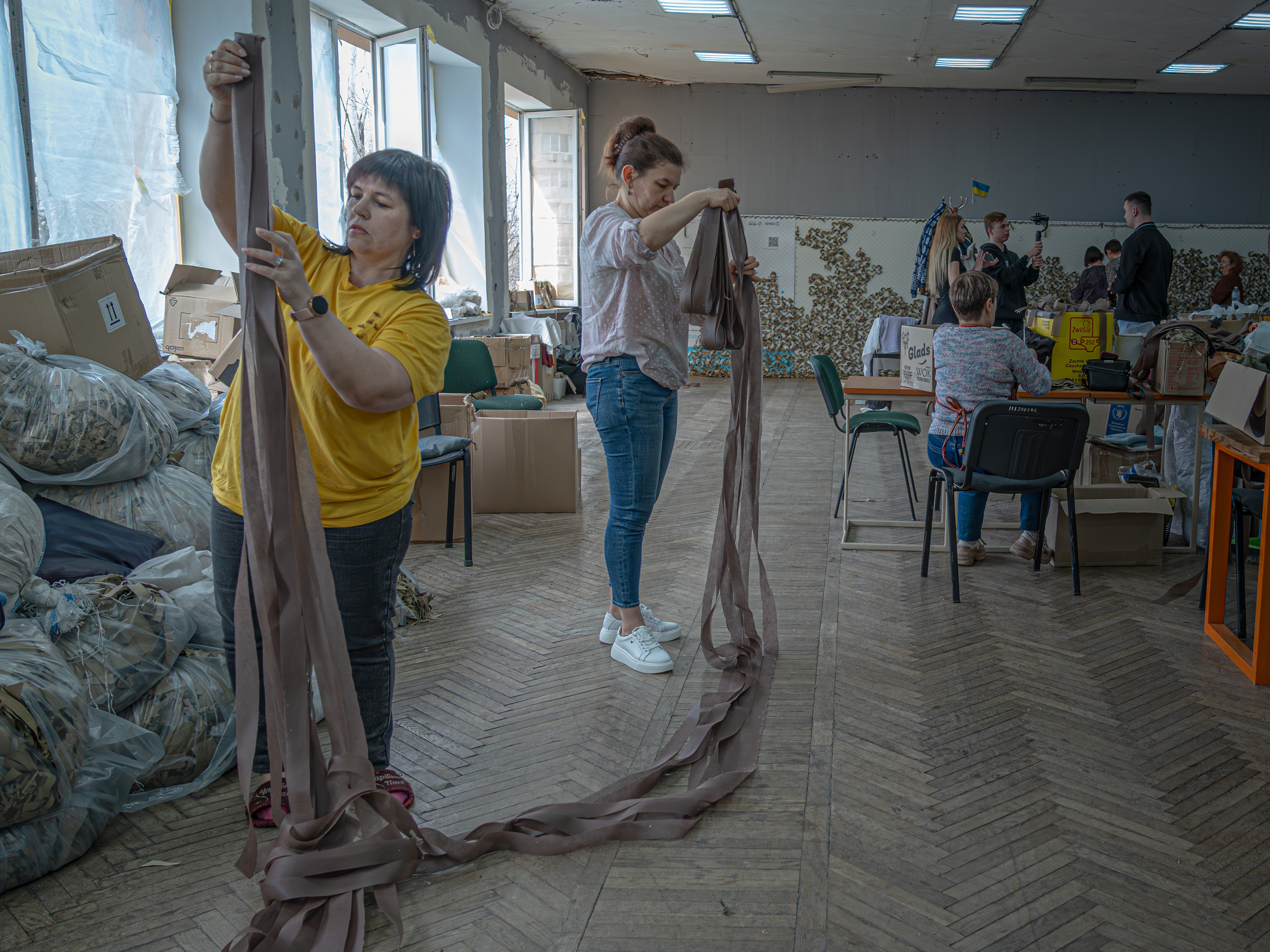 caption: Displaced Ukrainians weave camouflage netting for the military in Zaporizhia Youth Center on March 19.