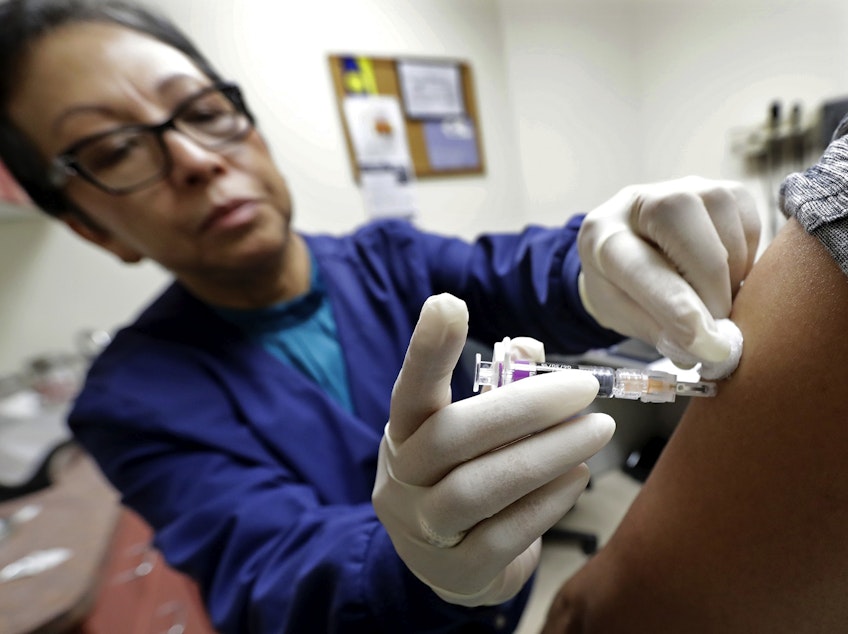 caption: Ana Martinez, a medical assistant at the Sea Mar Community Health Center, gives a patient a flu shot, Thursday, Jan. 11, 2018 in Seattle.