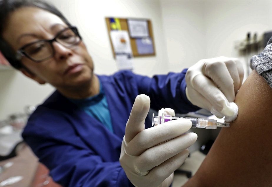 caption: Ana Martinez, a medical assistant at the Sea Mar Community Health Center, gives a patient a flu shot, Thursday, Jan. 11, 2018 in Seattle. 