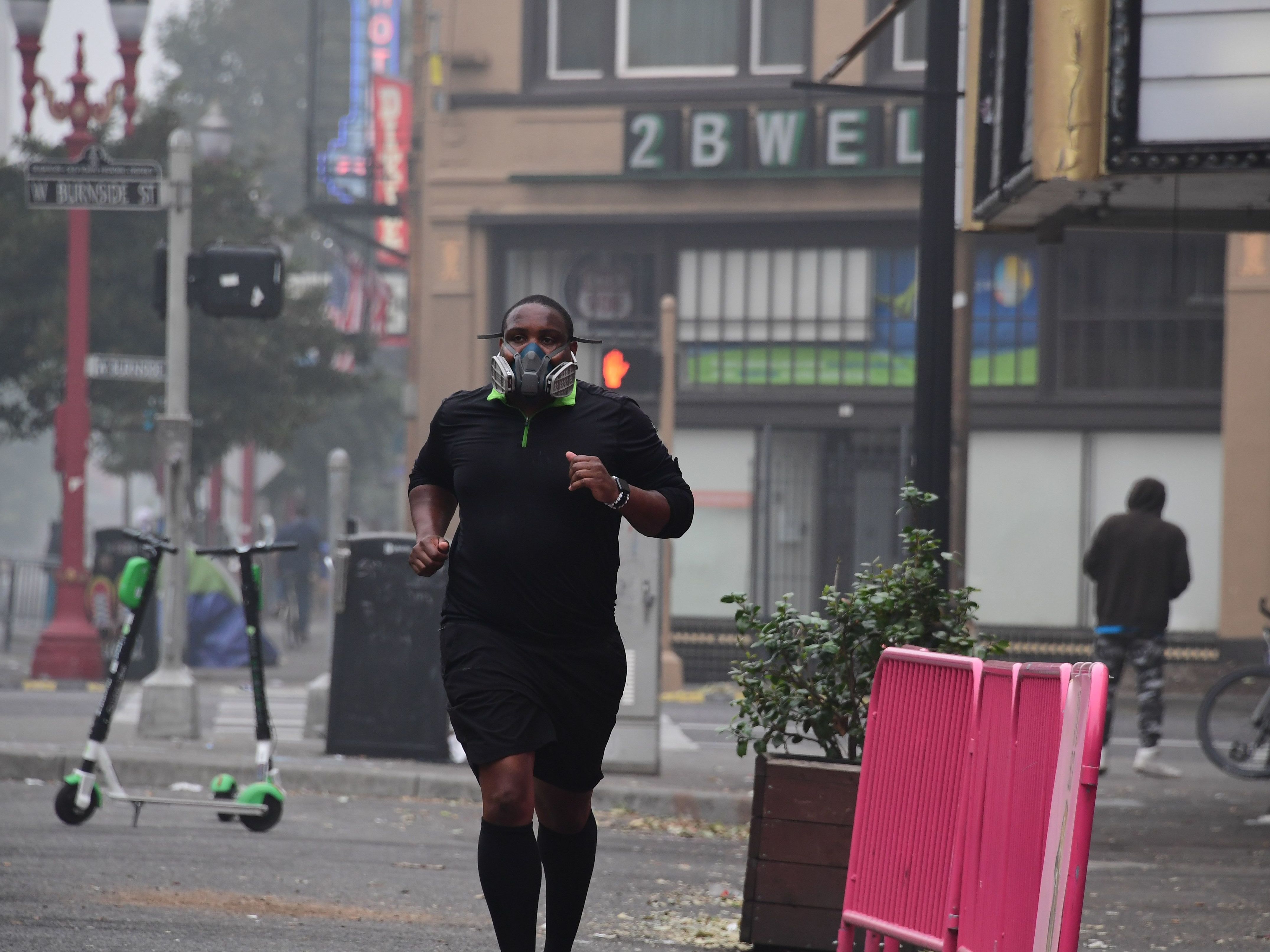 caption: A Portland, Ore., resident wears a respirator to protect himself from wildfire smoke as he jogs in downtown in September 2020.