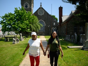 caption: Karen Williams (left) holds hands with her daughter, Lena Powell, while walking through St. Michael's Lutheran Churchyard in Philadelphia. Williams, who is disabled, bought a life insurance policy to pay for her funeral, but it caused her to lose access to Supplemental Security Income (SSI) benefit checks that she relies on to pay bills.