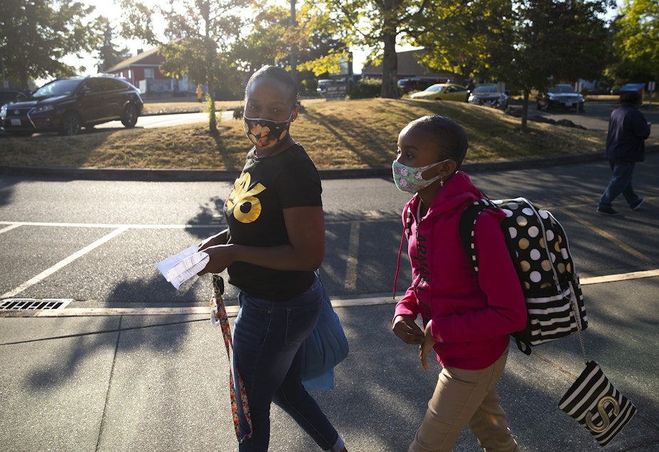 caption: Danishar Dorsey walks with her daughter, Serenity Woods, to her first day of 5th-grade at Mount View Elementary school on Thursday, September 2, 2021, in Seattle.