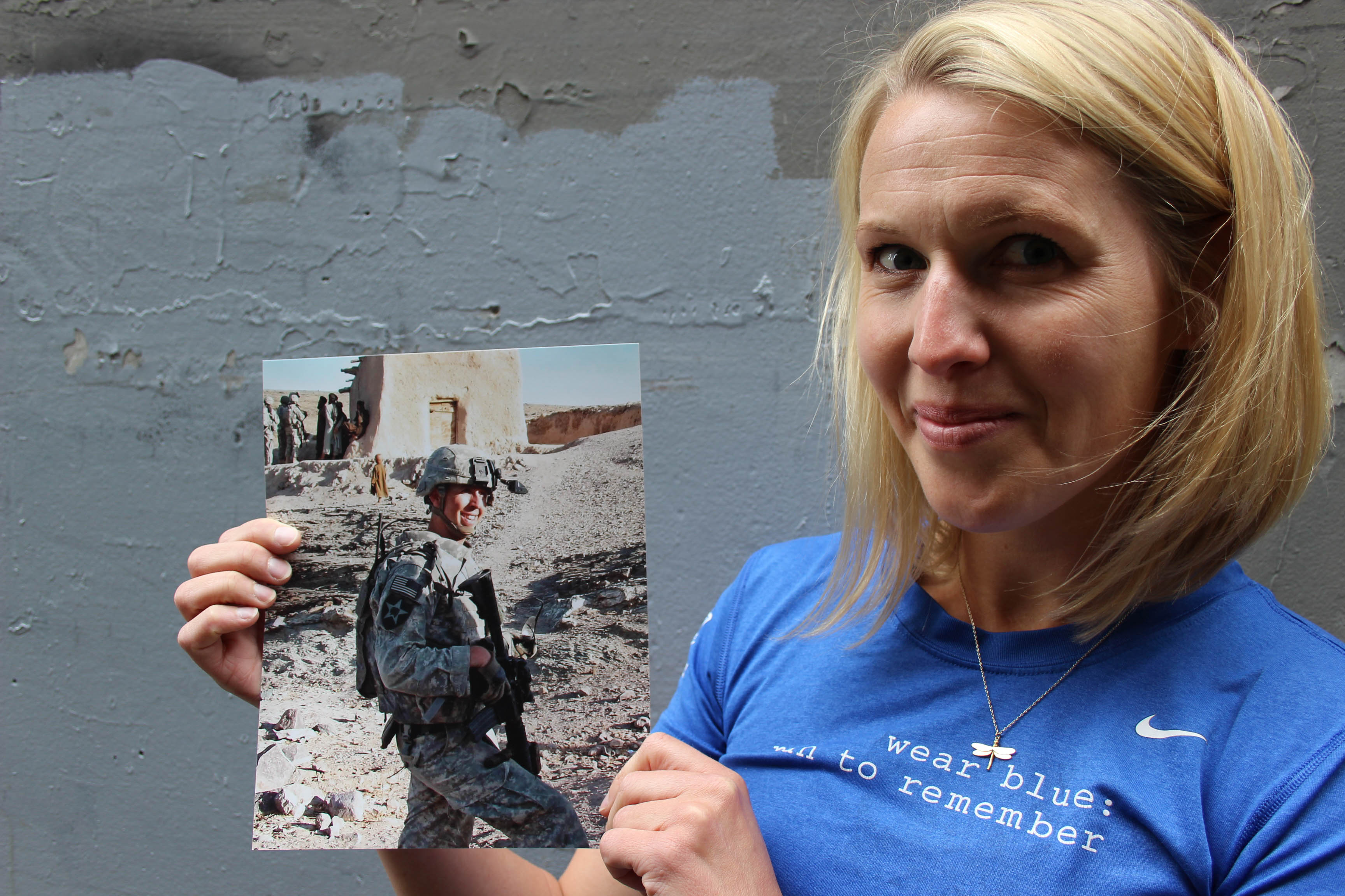 caption: Lisa Hallett holding a photo of her husband John