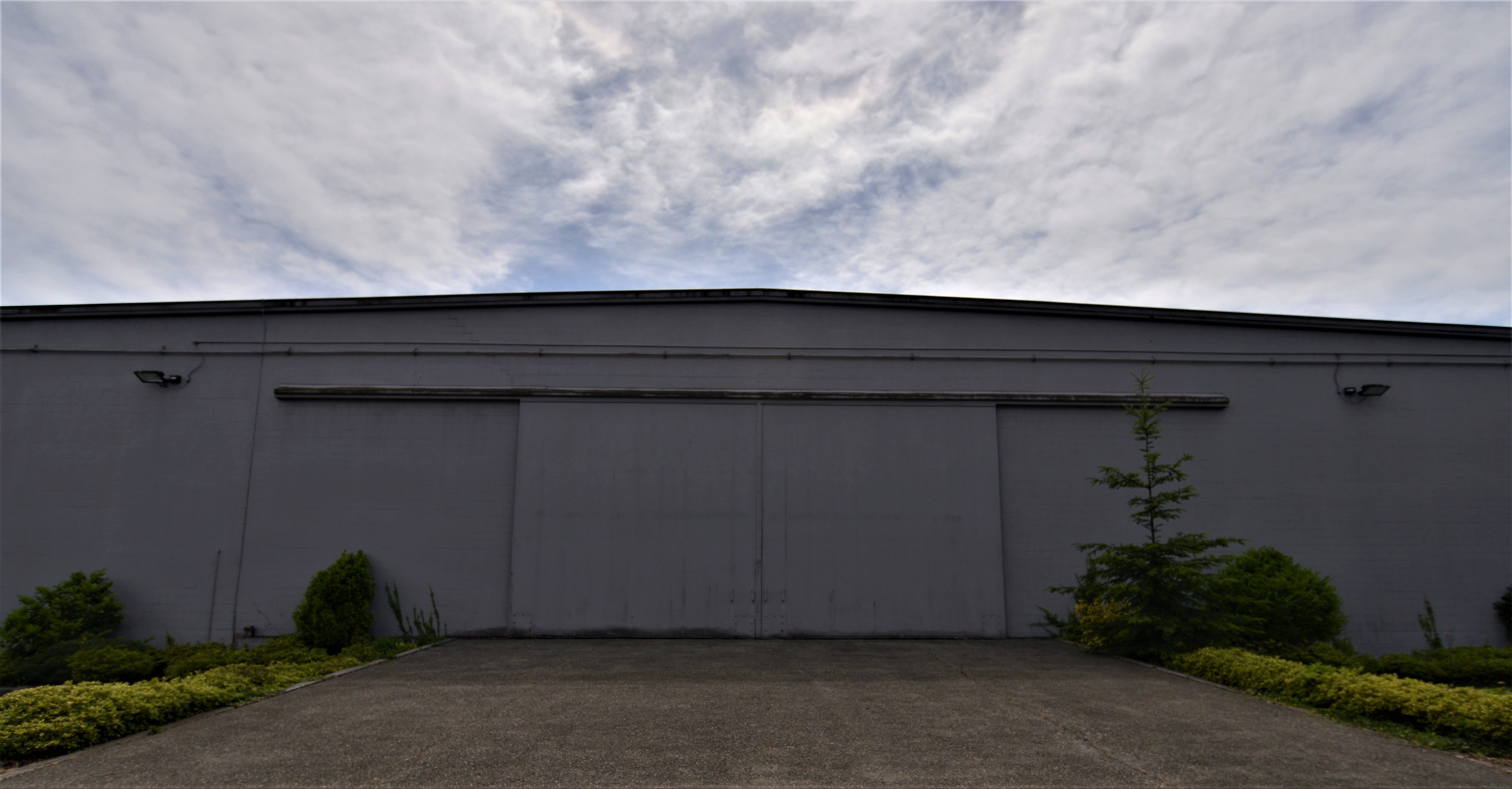 caption: The exterior of the Federal Records Center in Seattle reveals the hangar doors that hint at the building's first use: aircraft assembly plant.