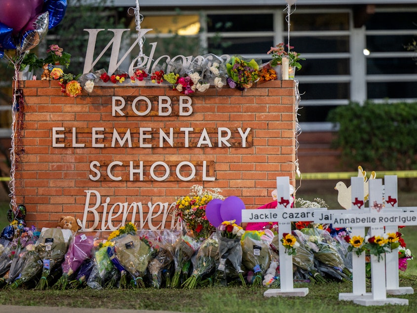 caption: A memorial is seen surrounding the Robb Elementary School sign following the mass shooting at Robb Elementary School on May 26, 2022 in Uvalde, Texas.