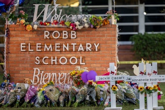 caption: A memorial is seen surrounding the Robb Elementary School sign following the mass shooting at Robb Elementary School on May 26, 2022 in Uvalde, Texas.
