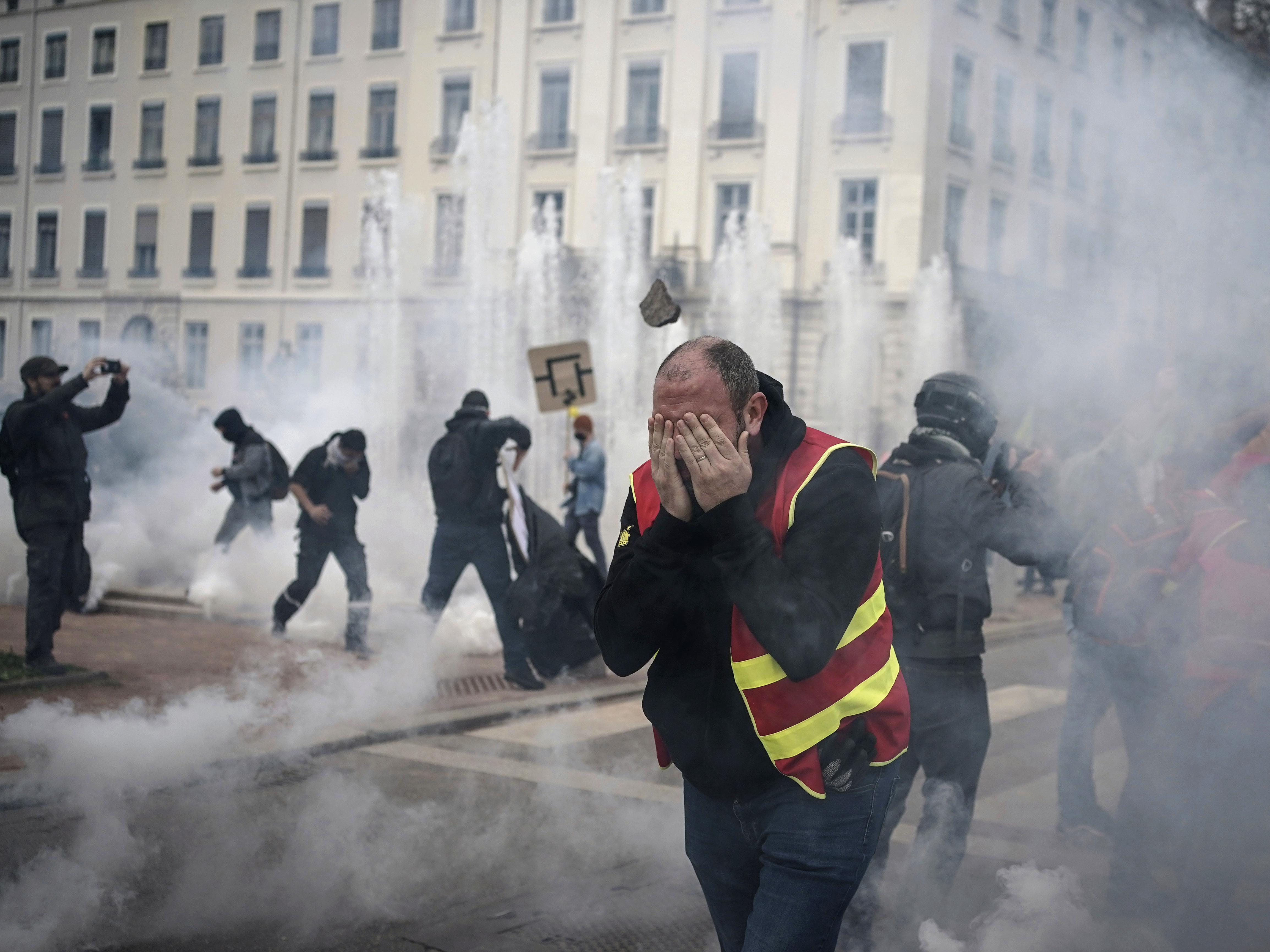 caption: Protesters run amid the tear gas during a demonstration in Lyon, central France, Thursday, March 23, 2023. French unions are holding their first mass demonstrations Thursday since President Emmanuel Macron enflamed public anger by forcing a higher retirement age through parliament without a vote.