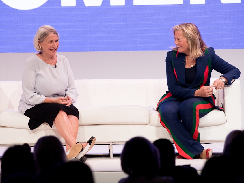 caption: Anita Dunn (left) speaks onstage with Hilary Rosen (right) at an event titled "Women Rule" in June 2018. That summer, Dunn and her communications firm began providing crisis communications for the then-Speaker of the Illinois House of Representatives regarding allegations of sexual harassment and retaliation.