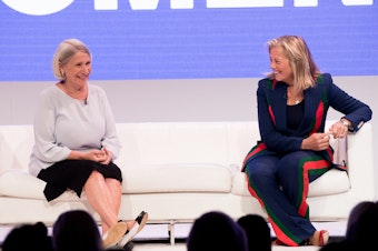 caption: Anita Dunn (left) speaks onstage with Hilary Rosen (right) at an event titled "Women Rule" in June 2018. That summer, Dunn and her communications firm began providing crisis communications for the then-Speaker of the Illinois House of Representatives regarding allegations of sexual harassment and retaliation.