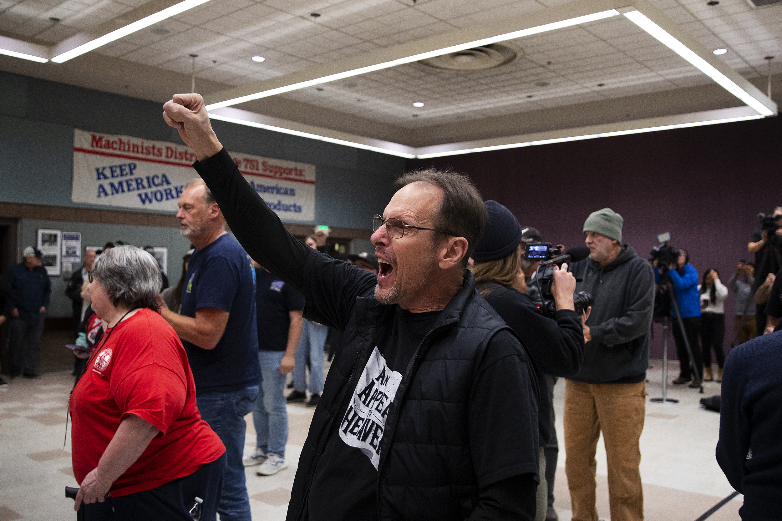 caption: Boeing machinist Perry Pirritano cheers after union leadership announced that the current contract offer was rejected by 64 percent of union members, on Wednesday, October 23, 2024, at IAM Hall in Seattle.