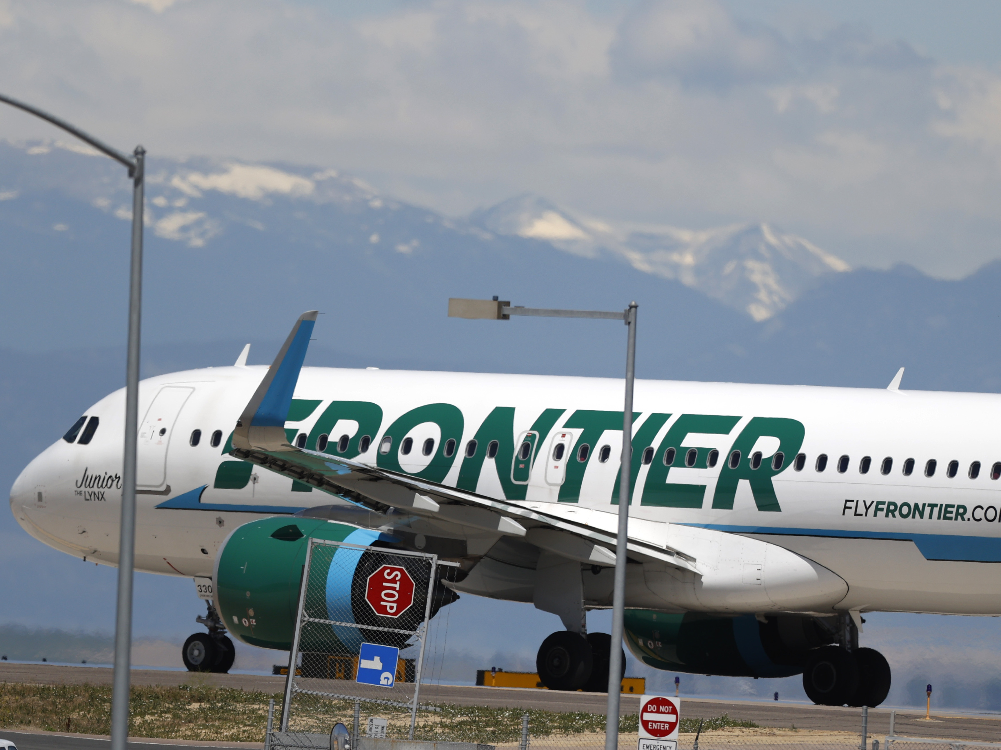caption: A Frontier Airlines aircraft at Denver International Airport in 2020. A 22-year-old passenger faces three misdemeanor charges after allegedly groping two flight attendants and assaulting a third.