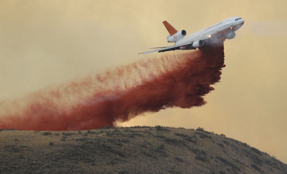 caption: An air tanker drops red fire retardant on a wildfire near Twisp, Wash., Wednesday, Aug. 19, 2015. High temperatures last month fueled fires in the Cascades and broke global records.