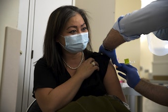 caption: Jennie Wu, Director of Urgent Clinics at Evergreen Health Medical Center, receives the first dose of the Moderna Covid-19 vaccine, administered by Dr. Ettore Palazzo on Wednesday, December 23, 2020, at Evergreen Health Medical Center in Kirkland. 