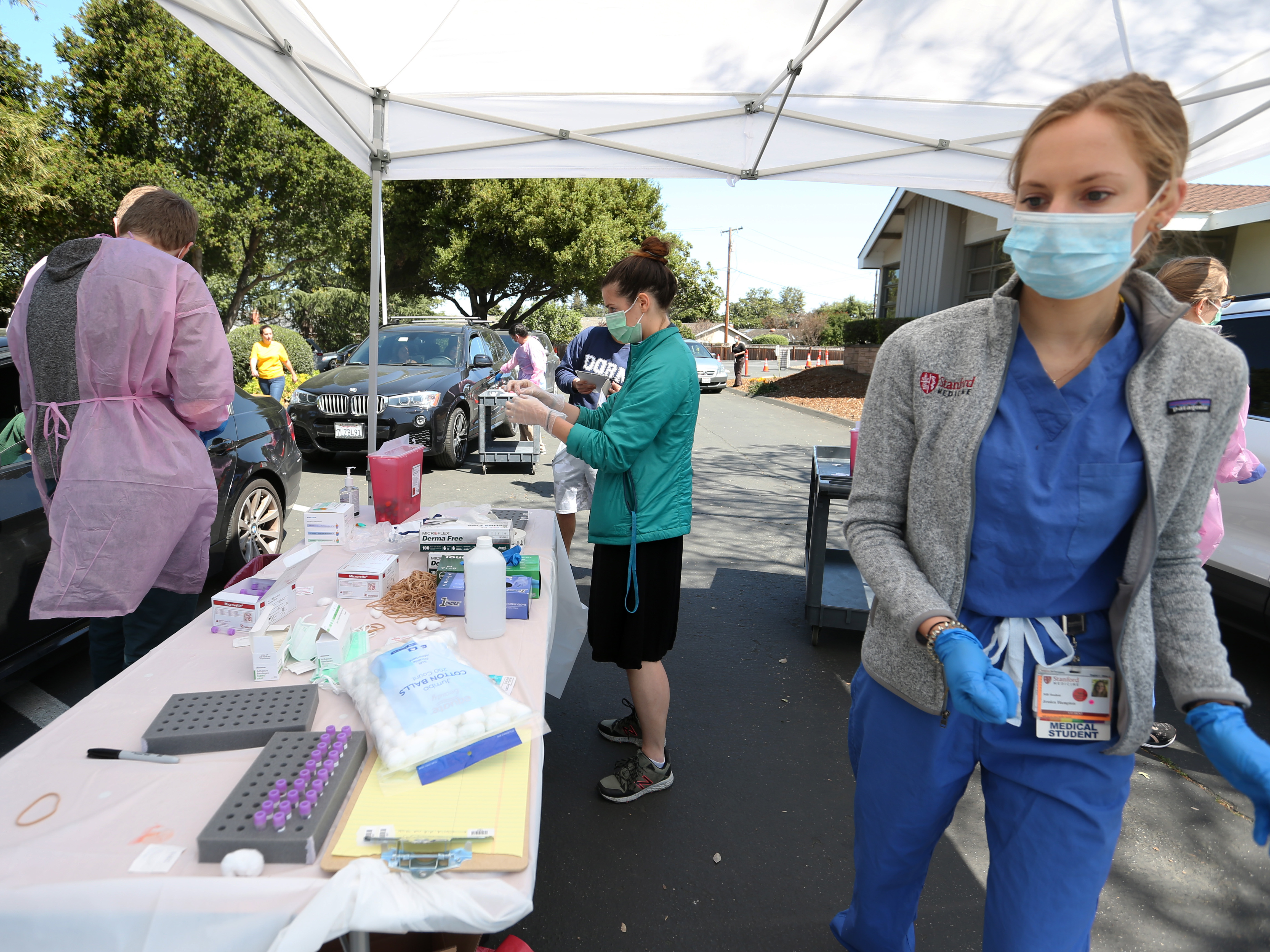 caption: Santa Clara County's medical examiner says a person who died on Feb. 6 has posthumously tested positive for COVID-19. Here, medical students, faculty and volunteers take blood samples during a coronavirus antibody study in Mountain View, Calif., earlier this month.