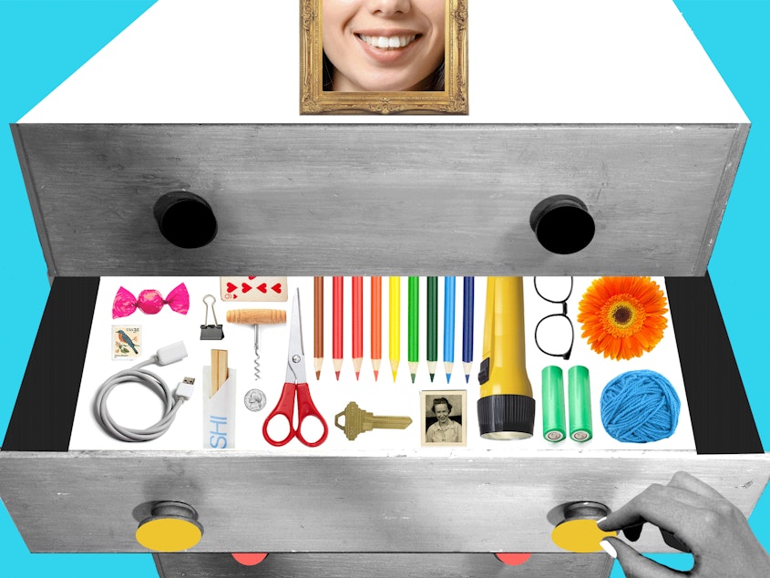 Collage of a black and white set of drawers with the middle drawer pulled out by a hand. Inside the drawer, in color, are pencils, scissors, a wine key, a key, a charge cord, playing card, chopsticks, batteries, a flashlight and other items typically found in a junk drawer, are colorful, impeccably organized. A framed photo of a smiling face sits atop the set of drawers.