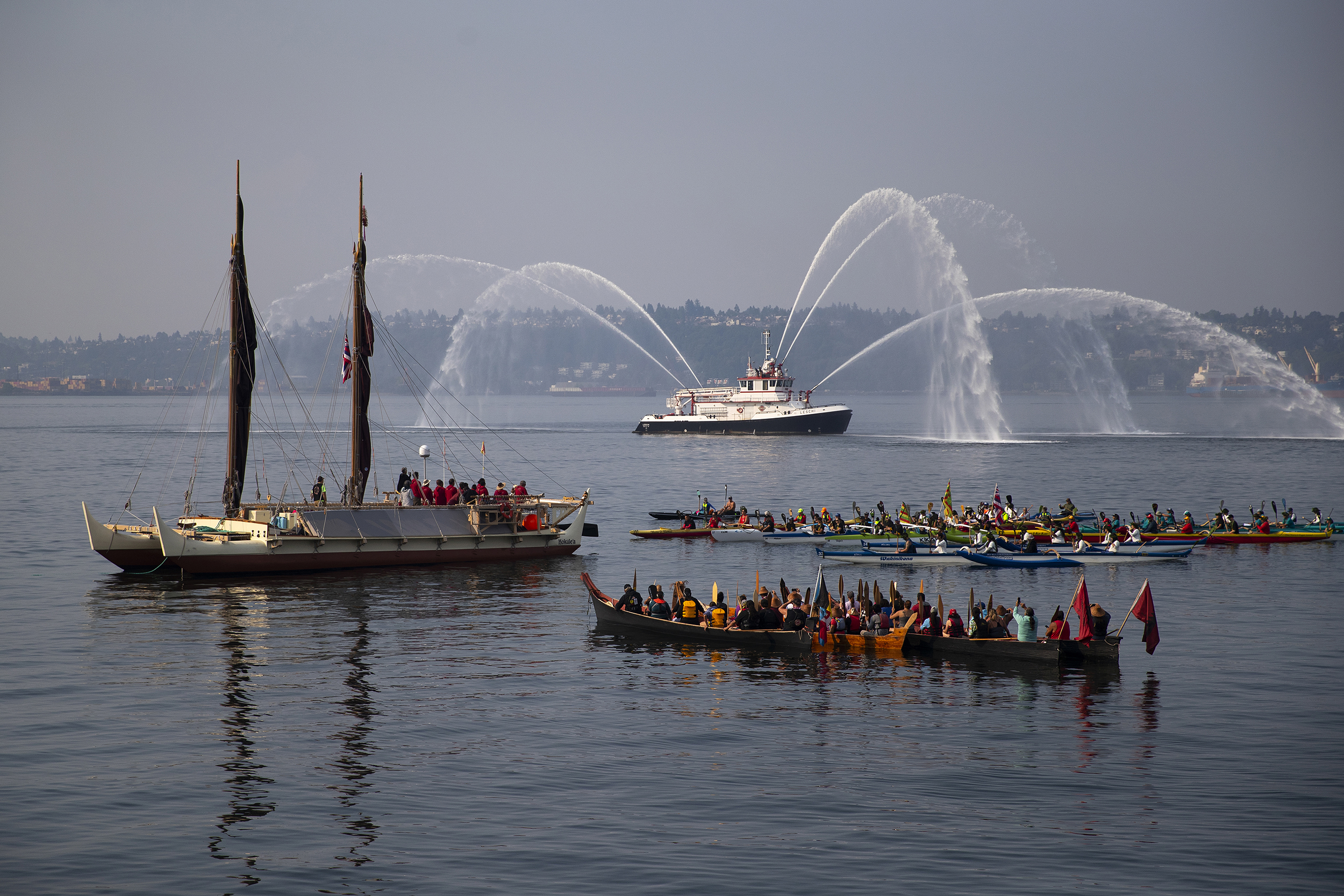 caption: Suquamish, Muckleshoot and Hawaiian canoes surround  Polynesian canoe Hokule'a during a water welcome ceremony on Elliot Bay on Saturday, August 26, 2023, in Seattle. 