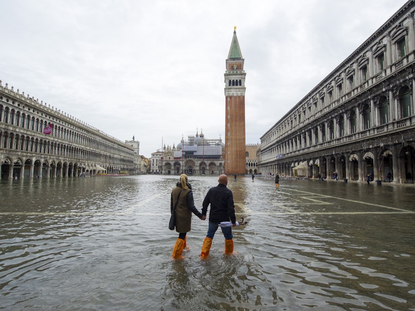 caption: A couple walks in a flooded Saint Mark's Square during high waters on Nov. 19, 2013, in Venice, Italy.