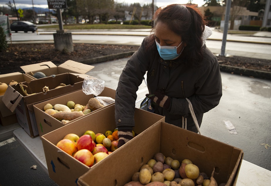 caption: Josefina Renteria, a volunteer and shopper, collects food during a weekly food share event on Saturday, December 10, 2022, in Bellingham.