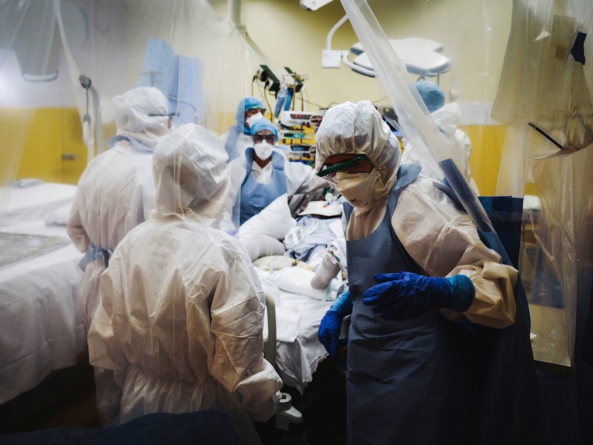 caption: Medical staff, seen at a Paris hospital Thursday, treat a patient infected with COVID-19. The worldwide death toll connected with the disease is nearing 100,000 — a startling statistic that may have seemed unthinkable just several months ago.