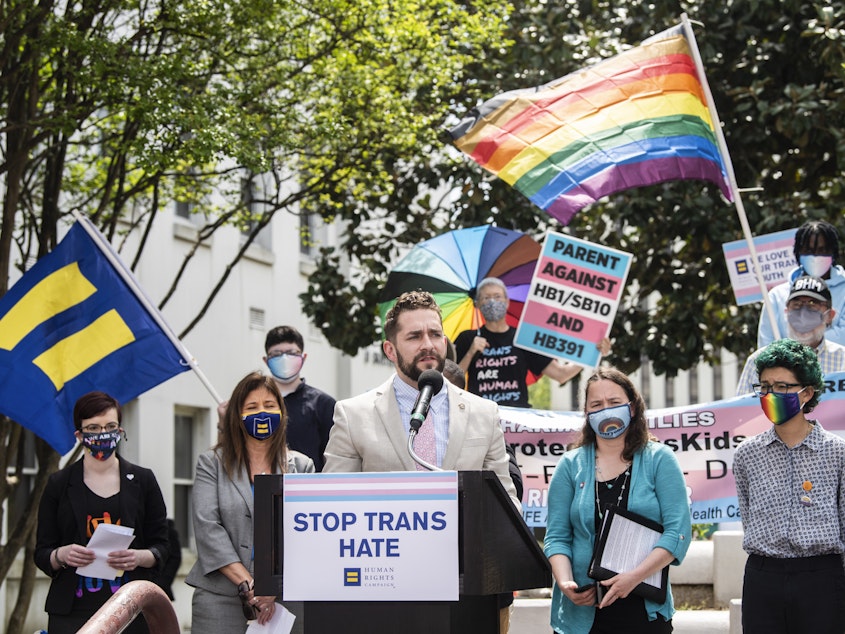 caption: Alabama Rep. Neil Rafferty speaks in support of transgender rights during a rally outside the Alabama State House in 2021. The state is using the<em> Dobbs</em> ruling, which overturned <em>Roe v. Wade</em> and ended abortion access as a federal right, to argue it has the authority to ban gender-affirming medical care.