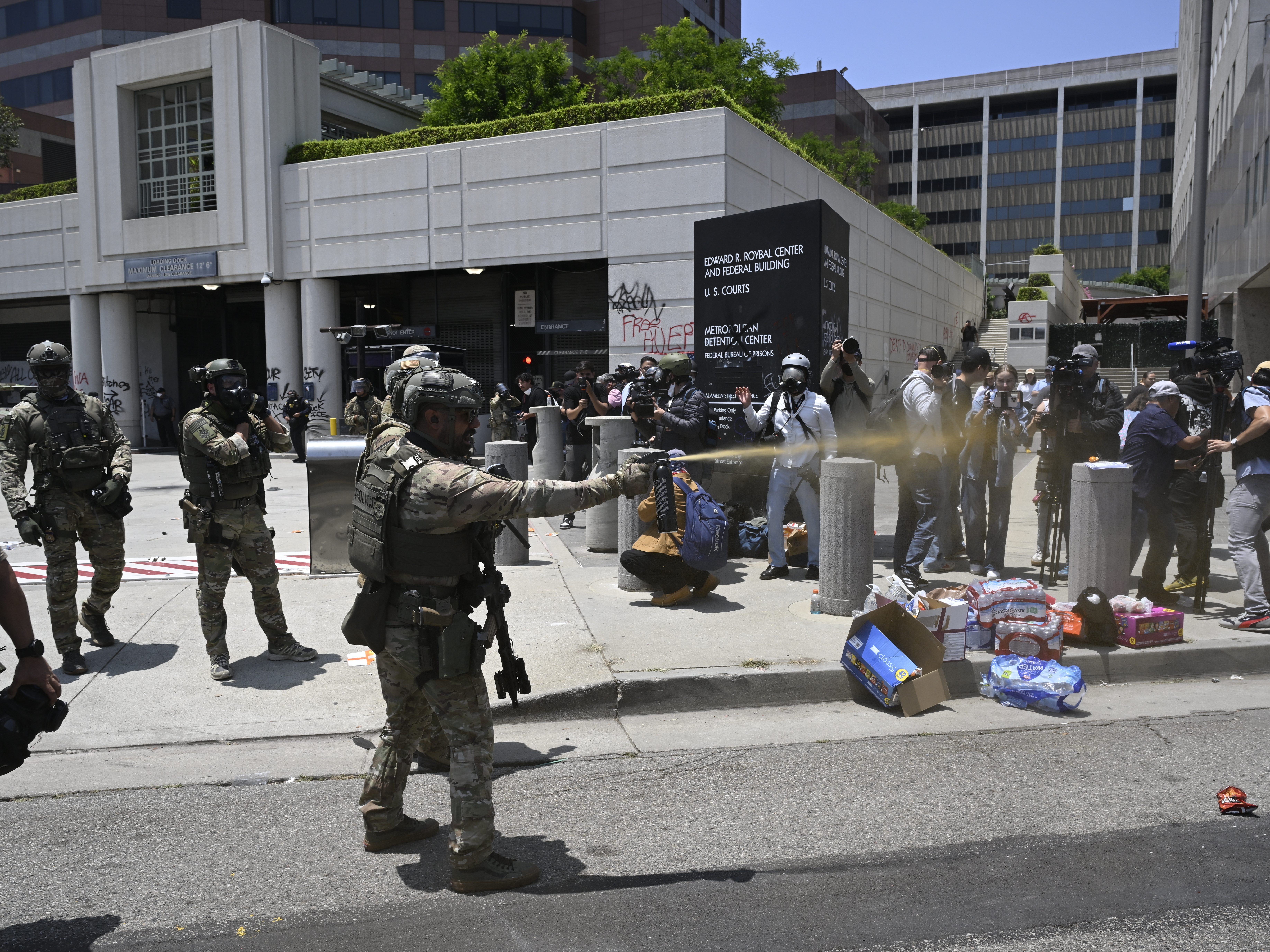 caption: ICE officers and members of the National Guard confront protesters outside of the Metropolitan Detention Center in Los Angeles.