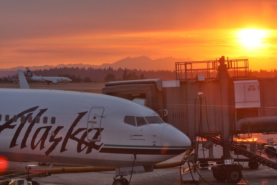 caption: An Alaska Airlines flight parked at SeaTac International Airport, with the Olympic mountains in the background. 