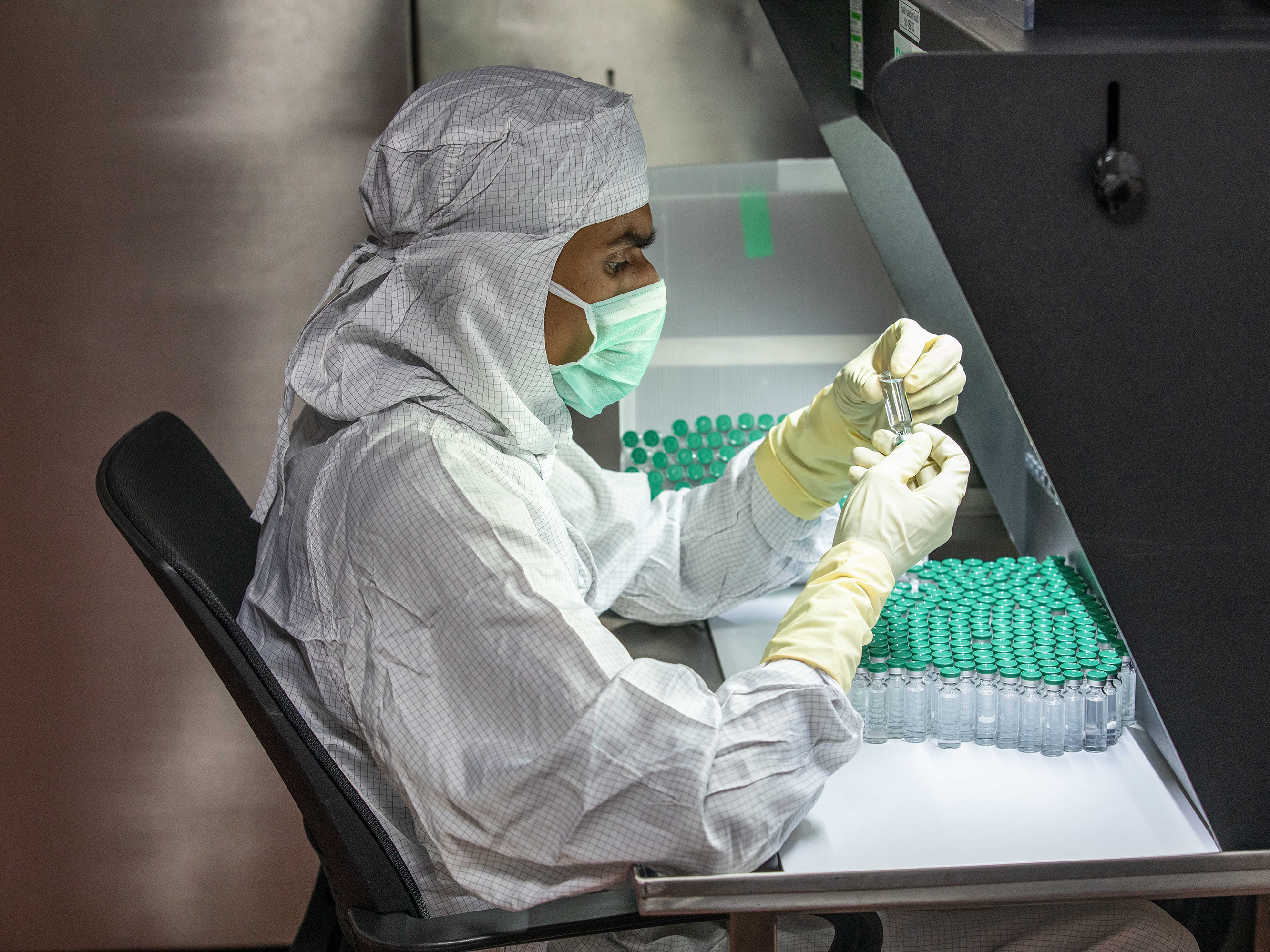 caption: A technician checks for any deficiencies in vaccine doses and vials.