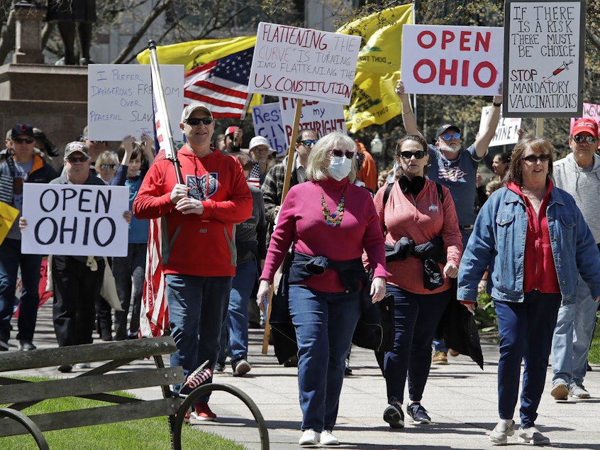 caption: People gather outside of the Ohio Statehouse in Columbus on Monday to protest the state's stay-at-home order that is in effect until May 1.